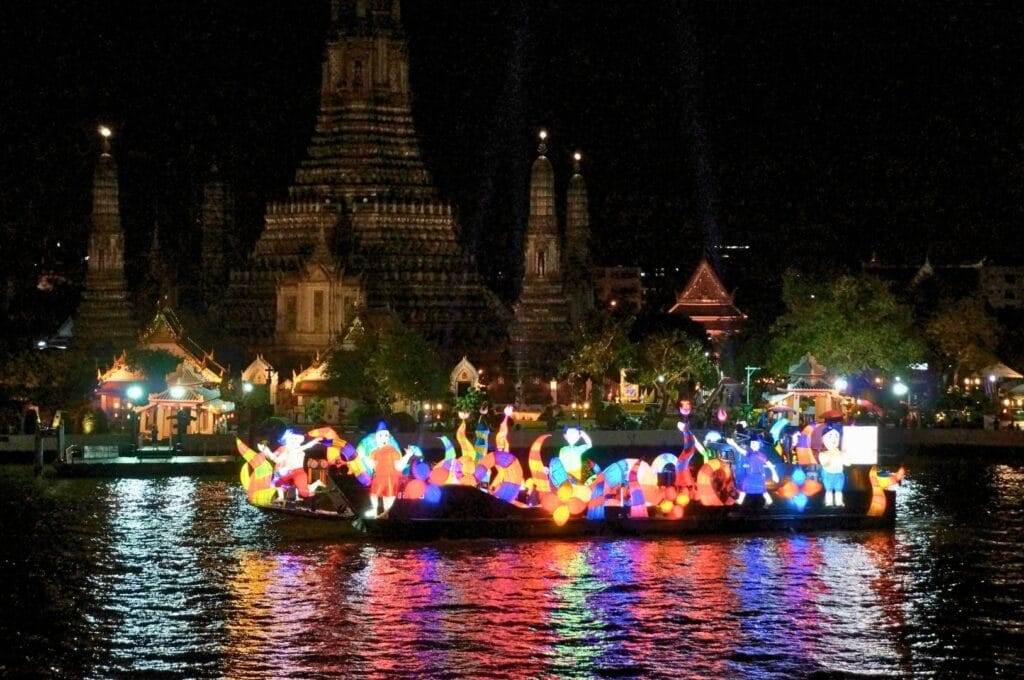 bateau avec des décorations lumineuses devant le temple Wat Arun à Bangkok