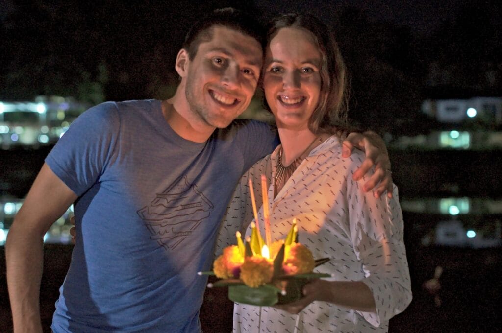Fabienne et Benoit tenant un krathong, un petit bateau avec des fleurs et une bougie
