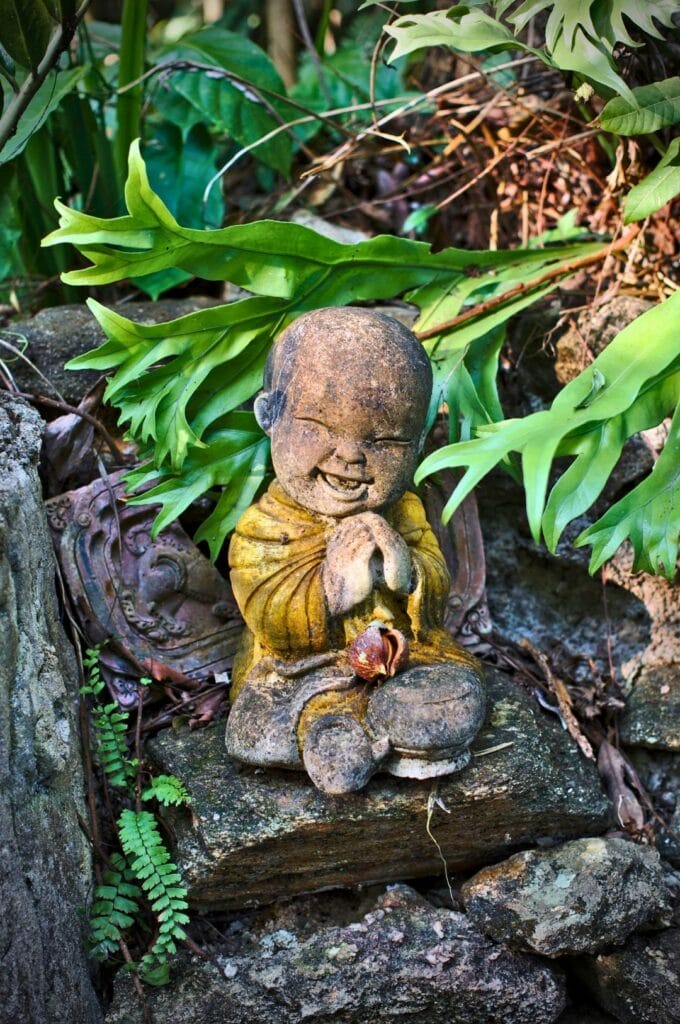 petite statue de moine dans la végétation du temple Wat Pha Lat