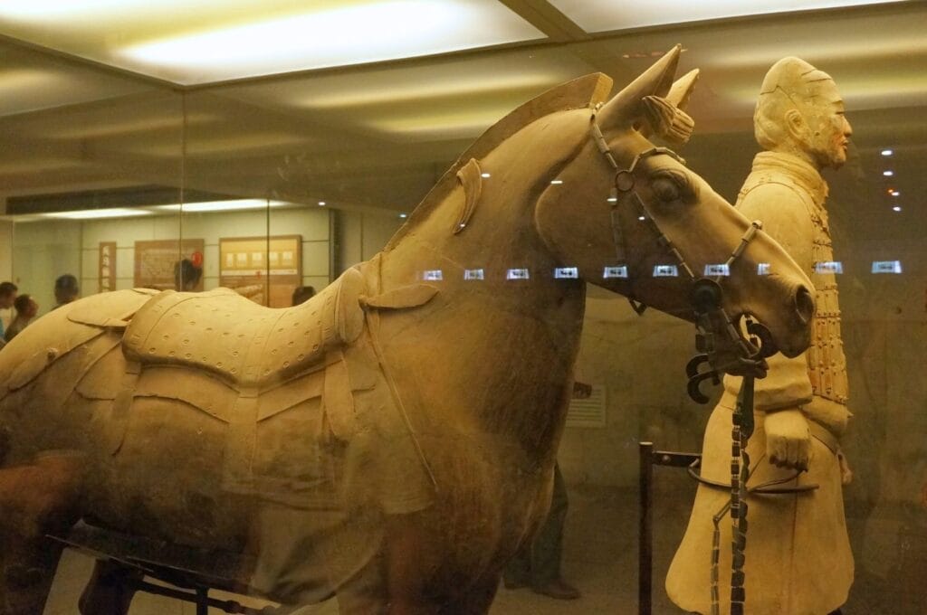 life-size clay statue of a horse and rider behind glass