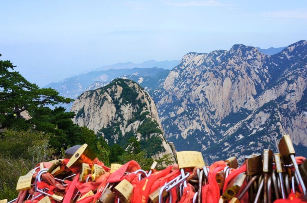 rubans rouges et cadenas accrochés au premier plan devant la vallée du Mont Hua