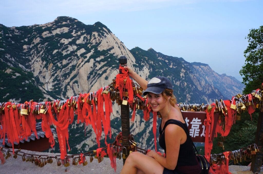 Fabienne devant les rubans rouges et les cadenas au sommet d'un pic