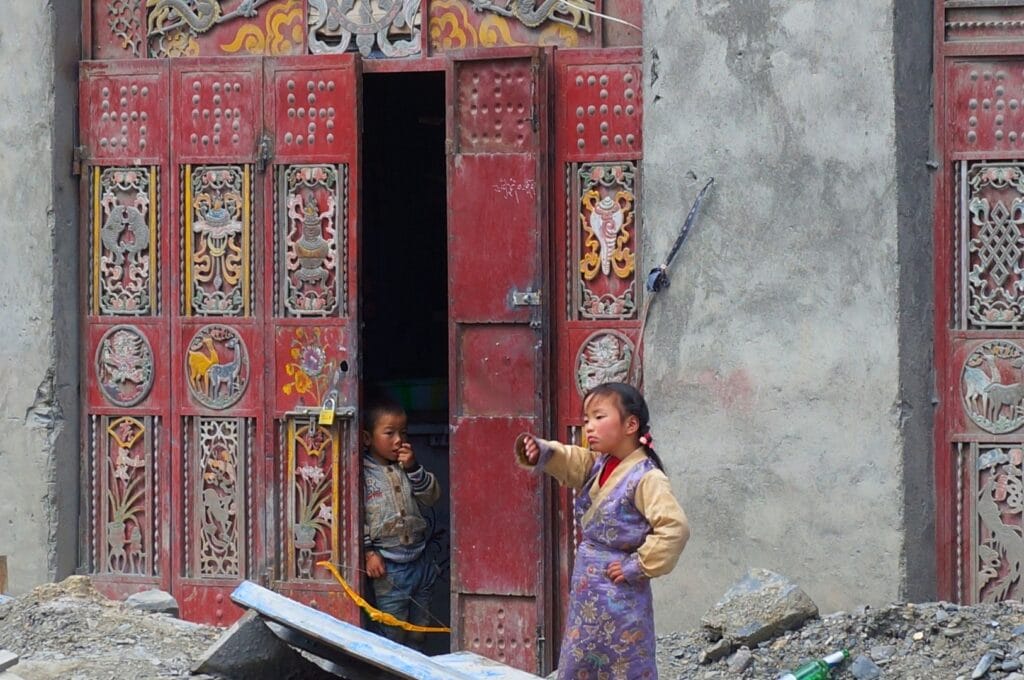 enfants autour d'une porte sculptée et peinte dans le Sichuan