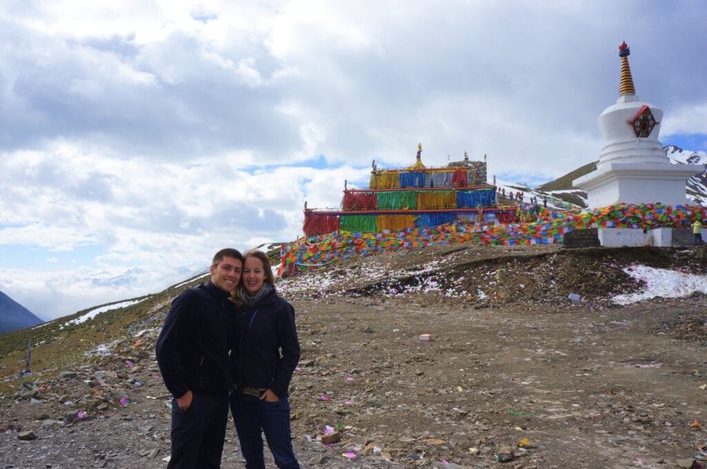 Fabienne et Benoit devant une stupa blanche avec des fanions colorés à côté