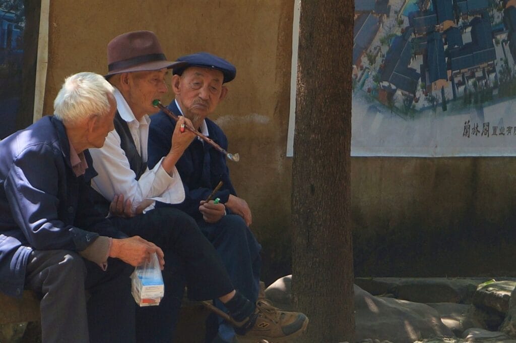 trois Chinois se partageant la pipe dans les rues de Shaxi