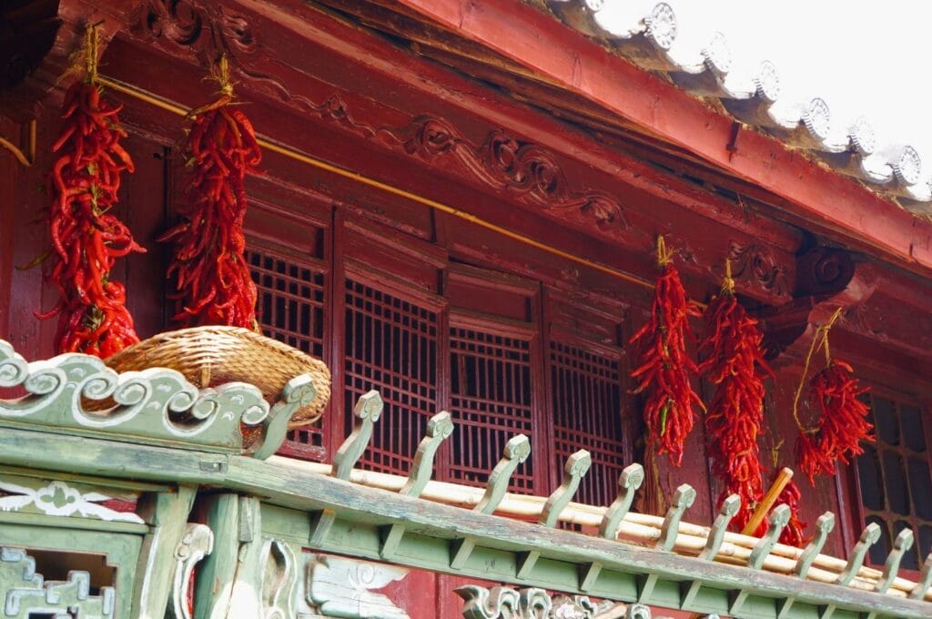 Grappes de piment rouge accrochées au toit d'une maison traditionnelle de Shaxi et séchant au soleil