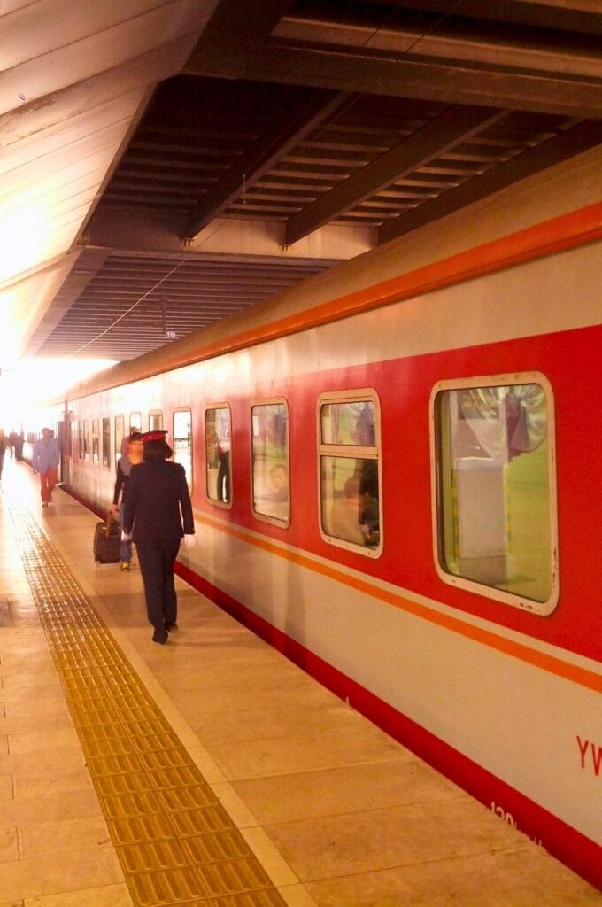 contrôleuse à côté d'un train blanc et rouge