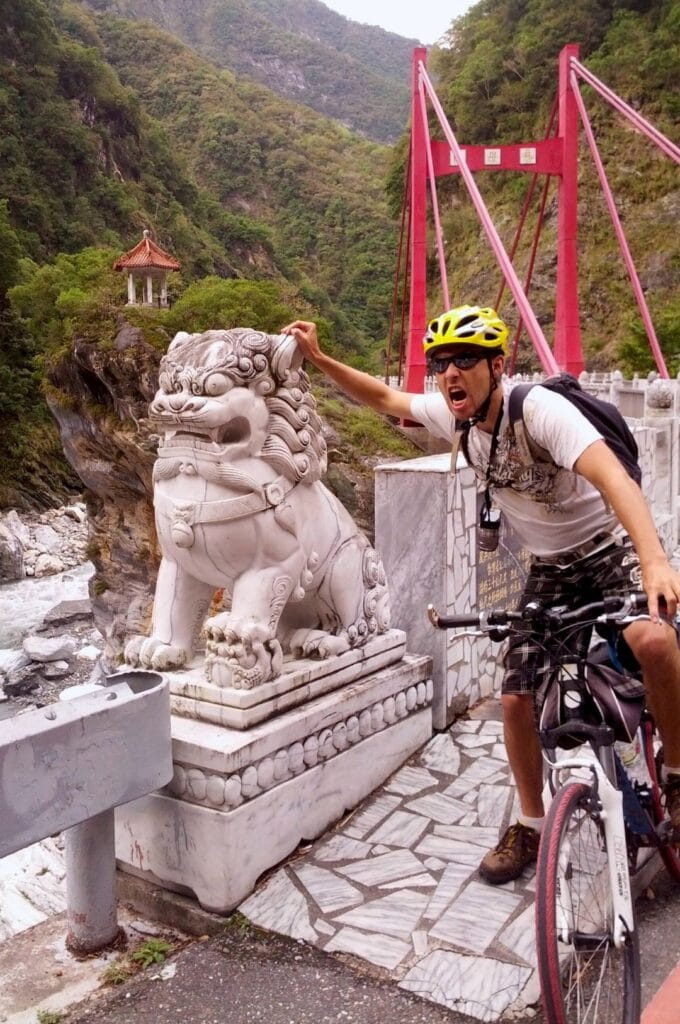 Benoit à vélo avec un lion en marbre devant le pont Cimu
