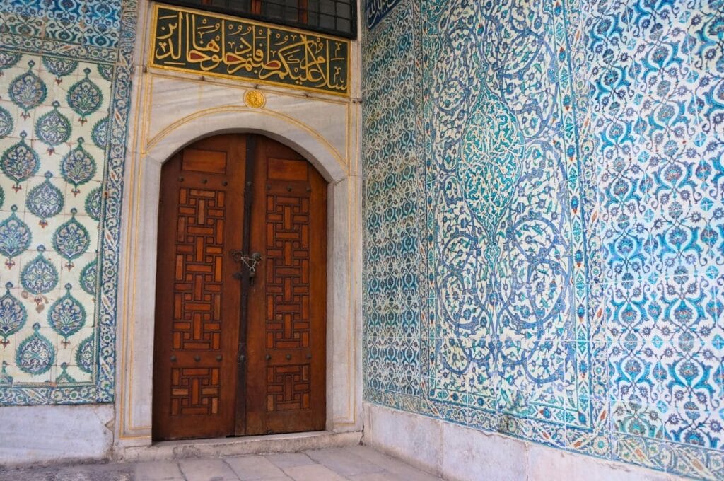 porte en bois et mur recouvert de mosaïques turquoise