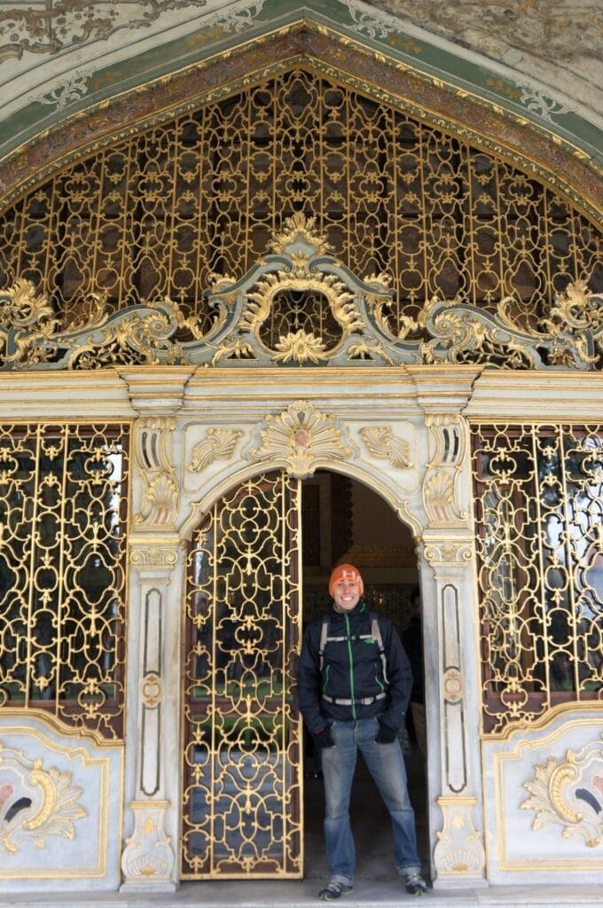 Benoit dans l'encadrement d'une porte dorée finement ouvragée