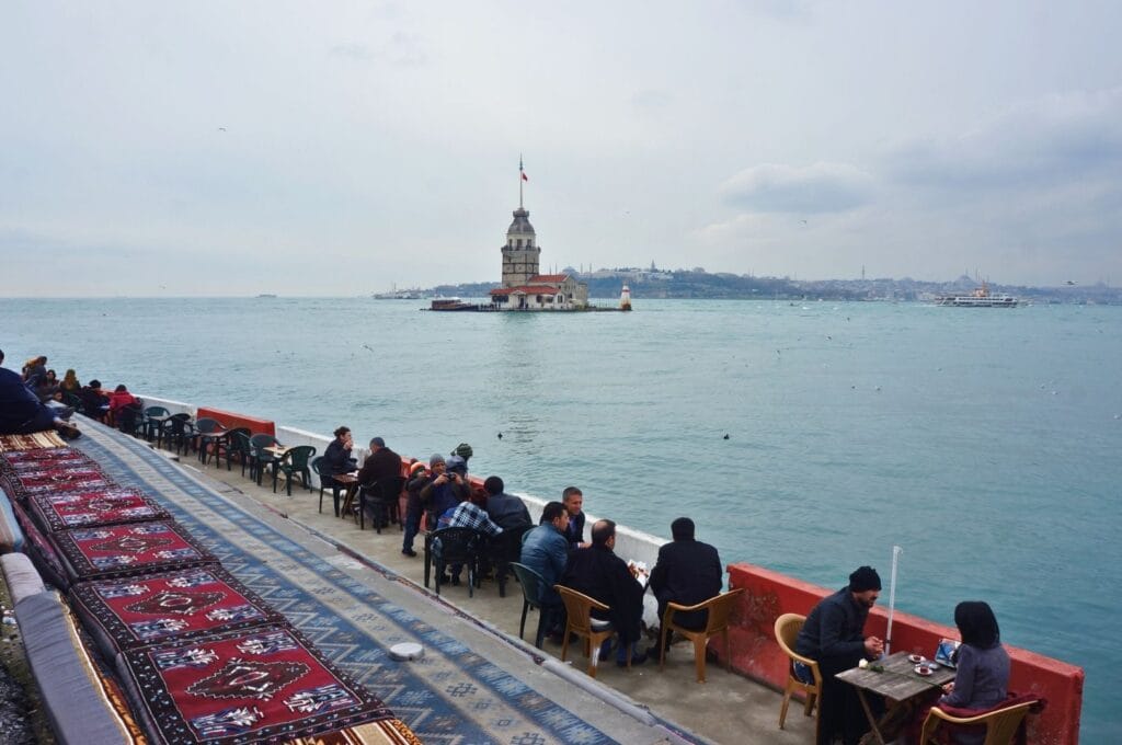 locaux prenant un café au bord du Bosphore avec la tour de Léandre en arrière-plan